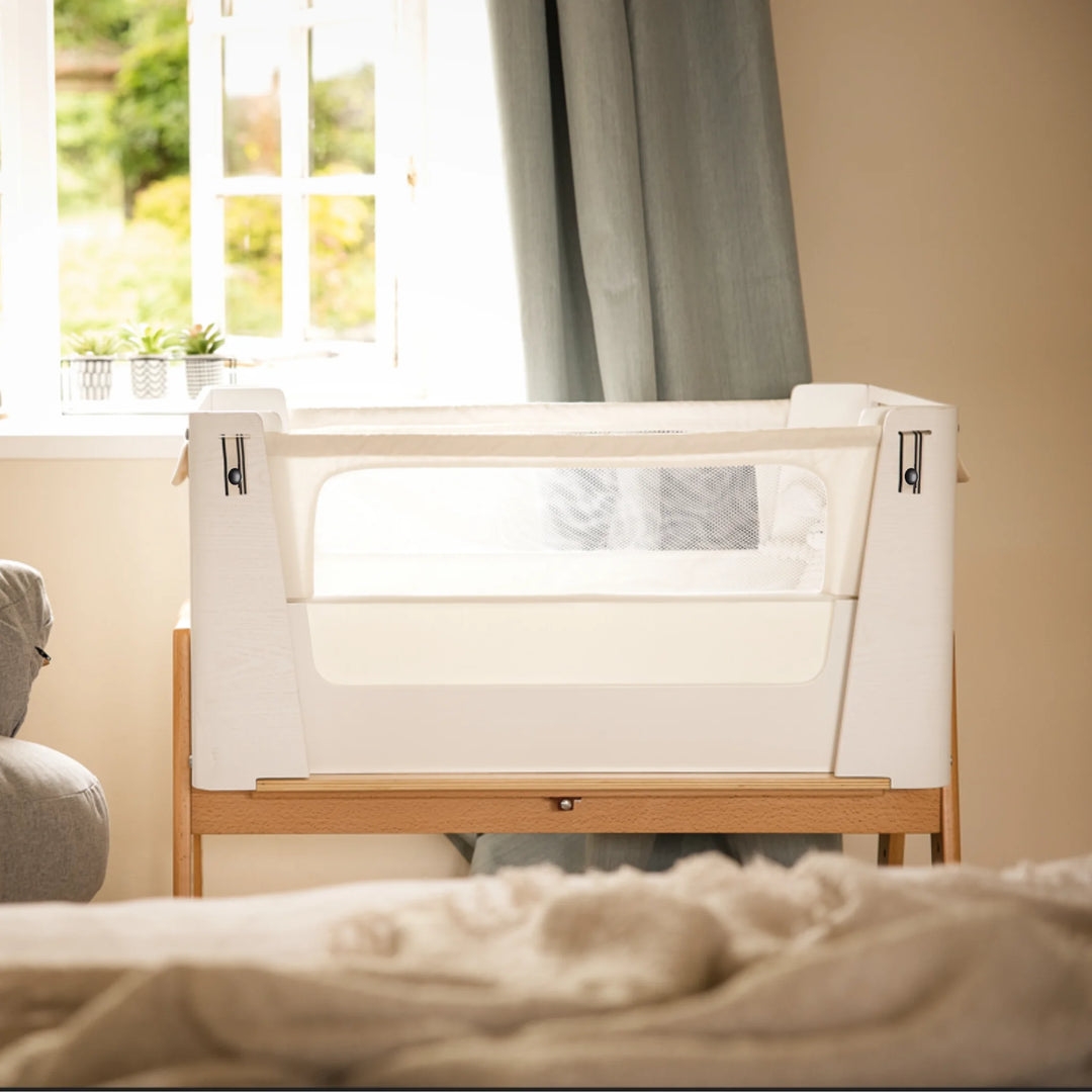 Hera real wood bedside crib in scandi white away from parents bed.