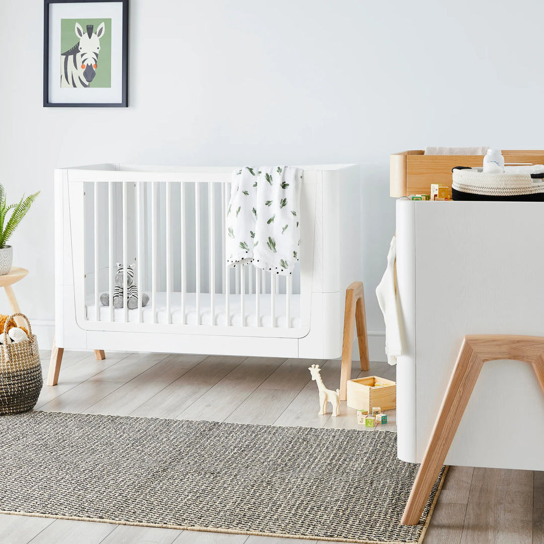 Hera Cot Bed Scandi White in bright nursery with matching dresser.