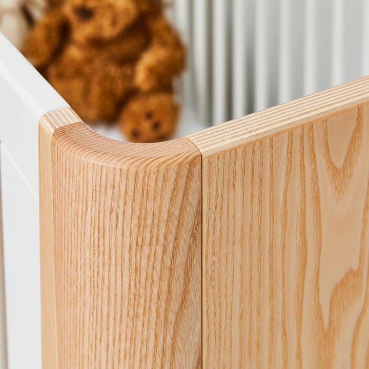 Hera Cot Bed corner close up showing real wood grain and smooth curved edge.