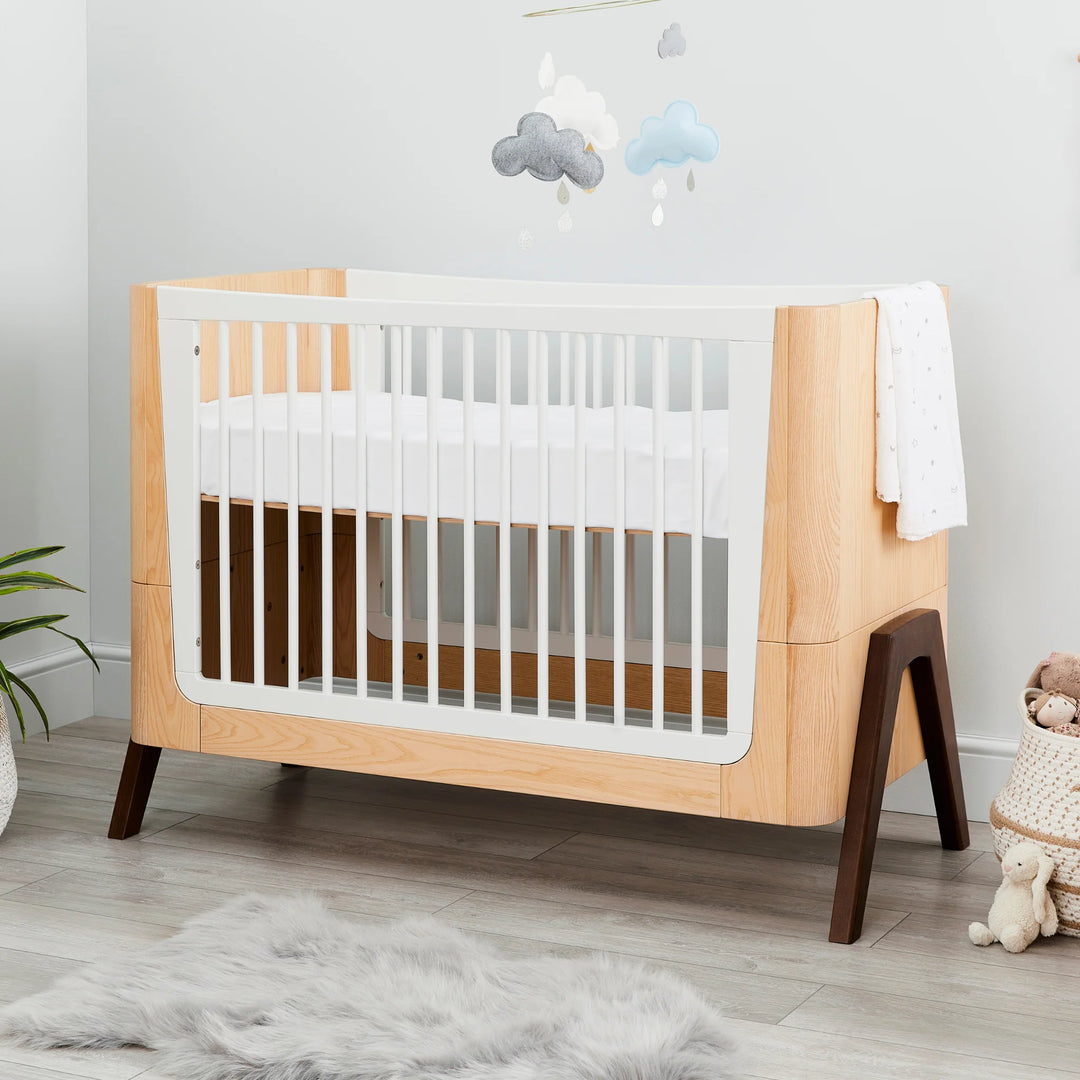 Hera Cot Bed styled in modern nursery with wooden flooring.