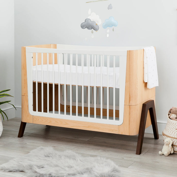 Hera Cot Bed styled in modern nursery with wooden flooring.