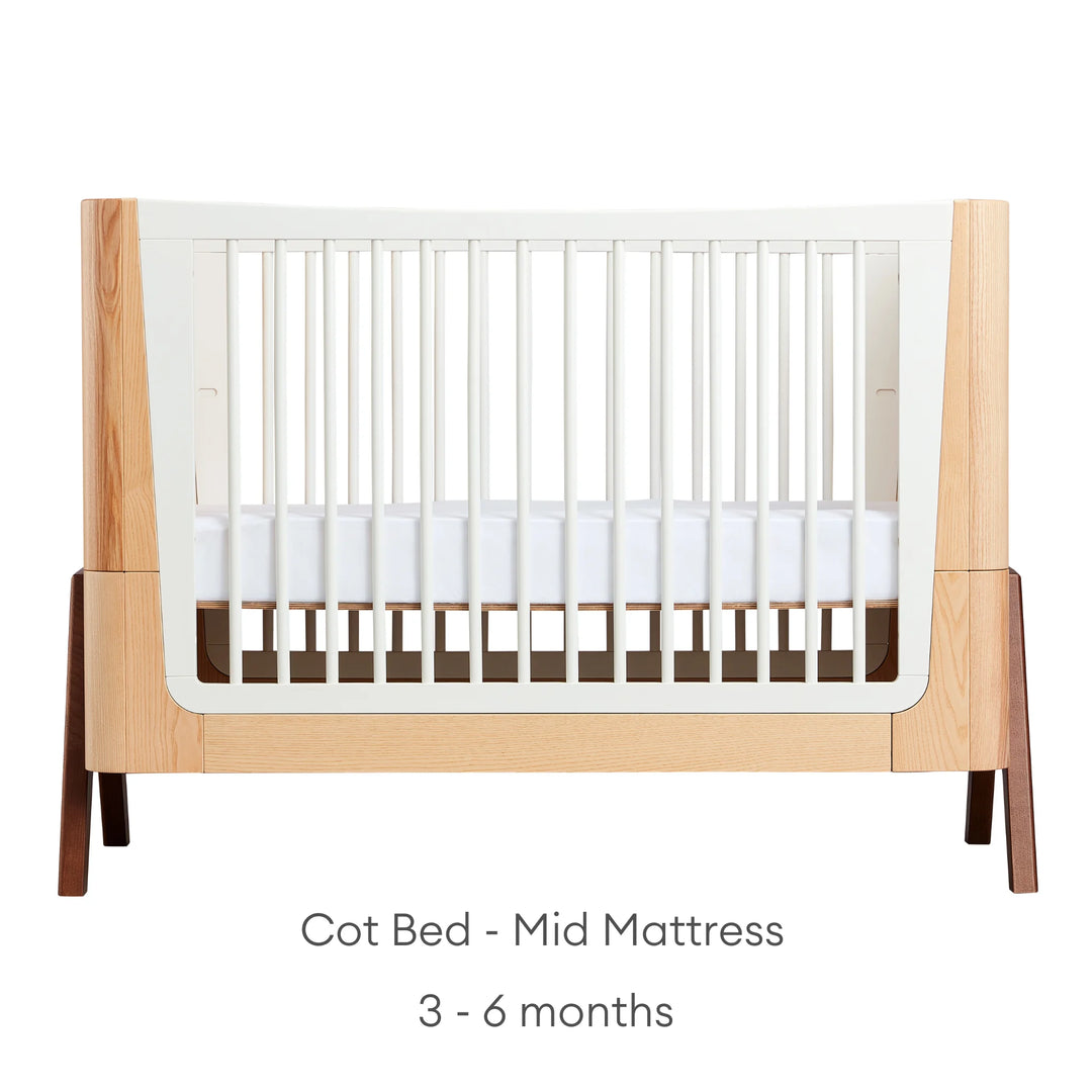Hera Cot Bed Natural Ash Walnut with mid mattress position for babies 3-6 months old.