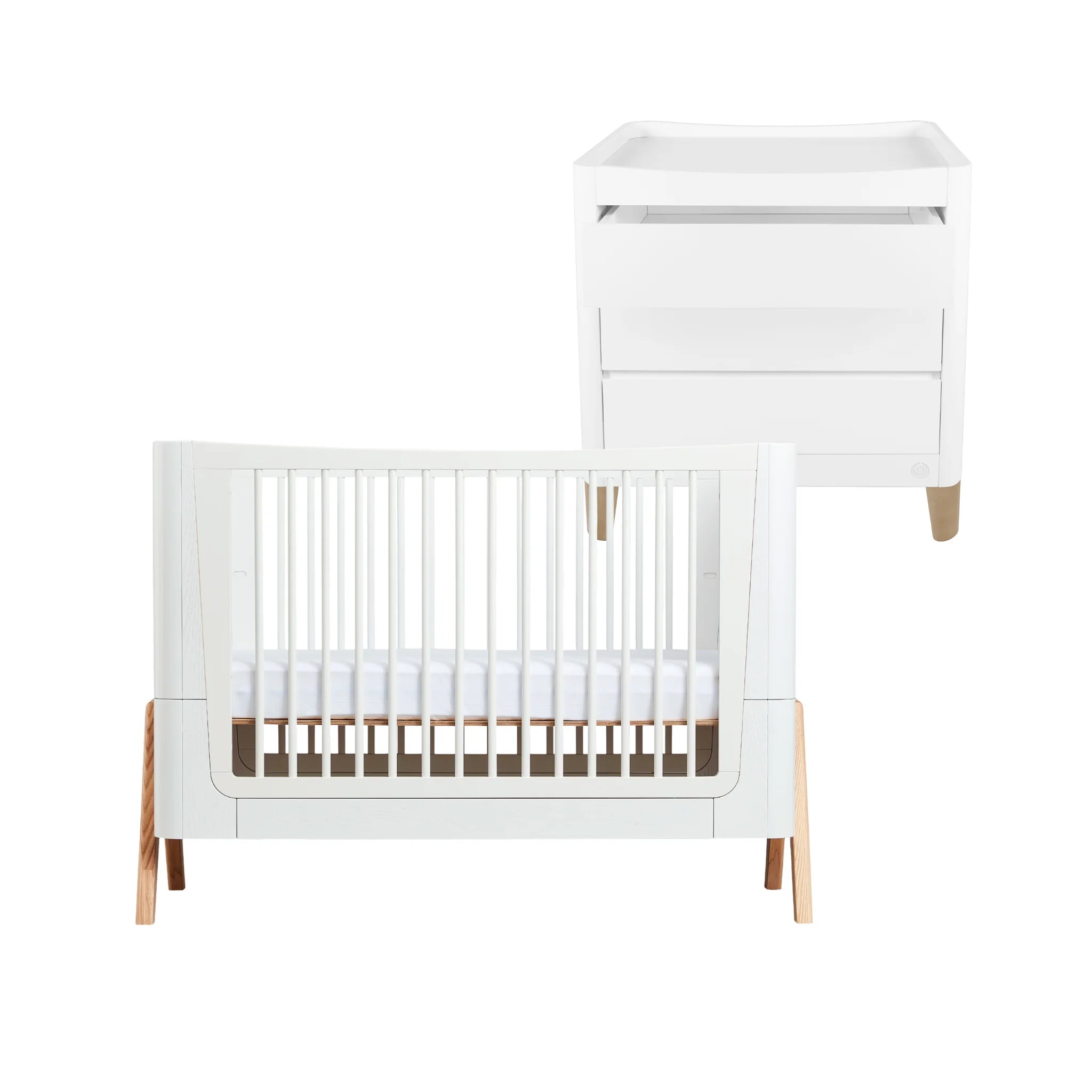 White Gaia Baby Hera cot bed with white slatted sides and light natural wood legs, paired with a matching white Serena changing dresser, displayed on a white background.