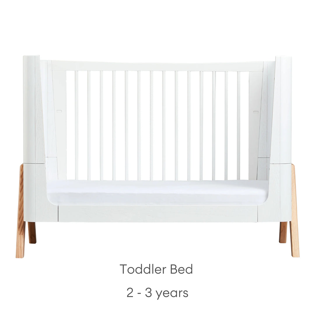 Front view of Gaia Baby Hera Cot Bed in scandi white, converted into Toddler Bed mode, with one side removed. Text reads: Toddler Bed suitable from 2 to 3 years.