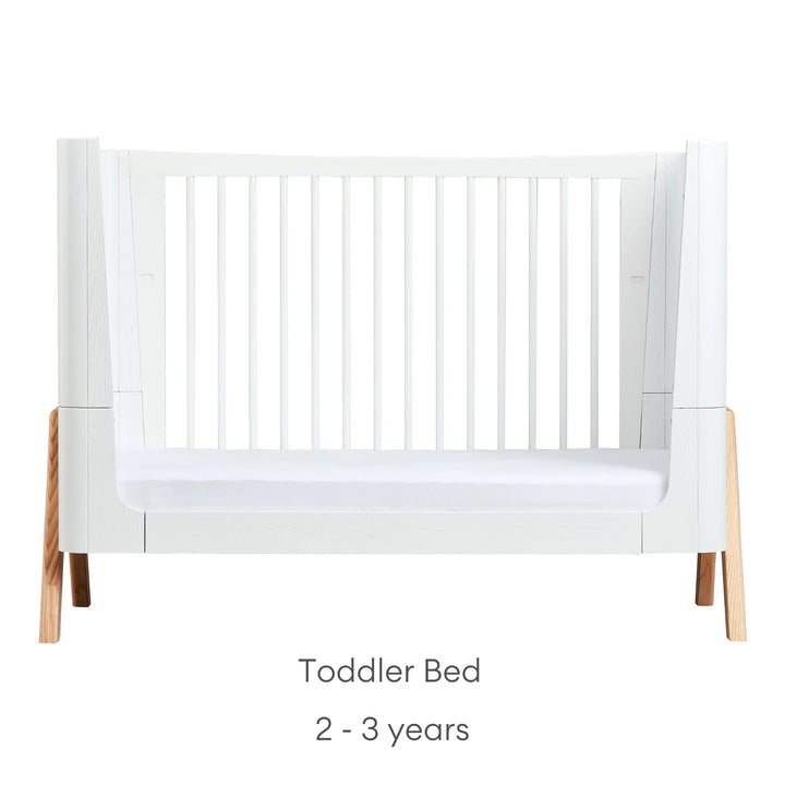 Front view of Gaia Baby Hera Cot Bed in scandi white, converted into Toddler Bed mode, with one side removed. Text reads: Toddler Bed suitable from 2 to 3 years.