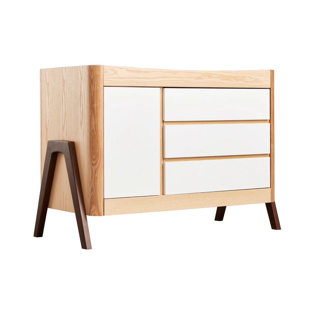 45 degree angle view of Gaia Baby Hera Nursery Dresser in white natural with 3 drawers, 1 cabinet door and a-frame legs in walnut wood.