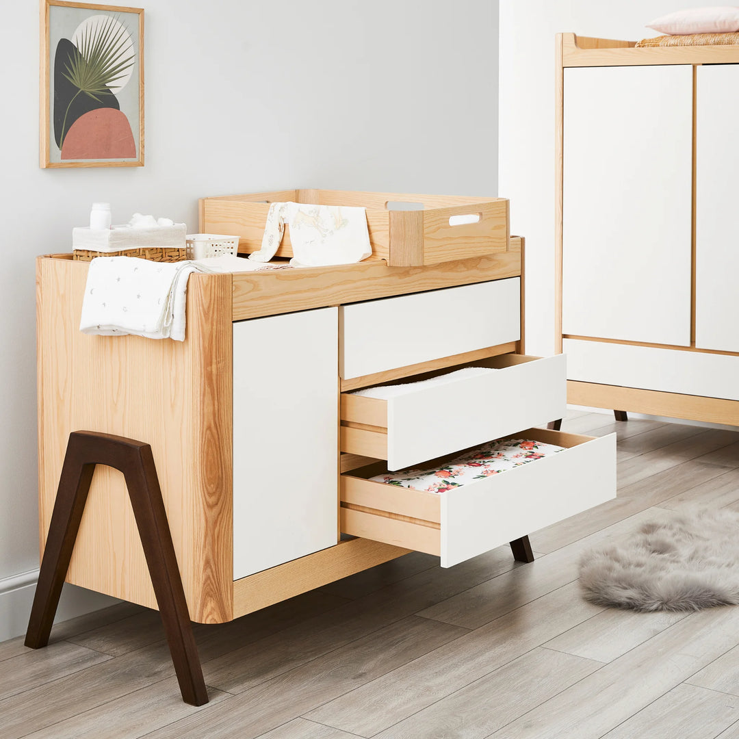 Hera Dresser with matching wardrobe and changing station with bottom two drawers opened showing ample storage.