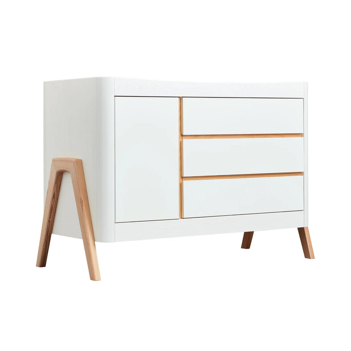 45 degree angle view of Gaia Baby Hera Nursery Dresser in scandi white with 3 drawers, 1 cabinet door and a-frame legs in natural wood.