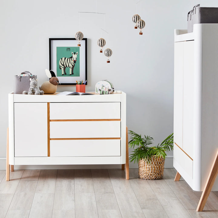 Gaia Baby Hera Dresser in scandi white with matching wardrobe styled in modern baby nursery using soft toys and baby changing accessories.
