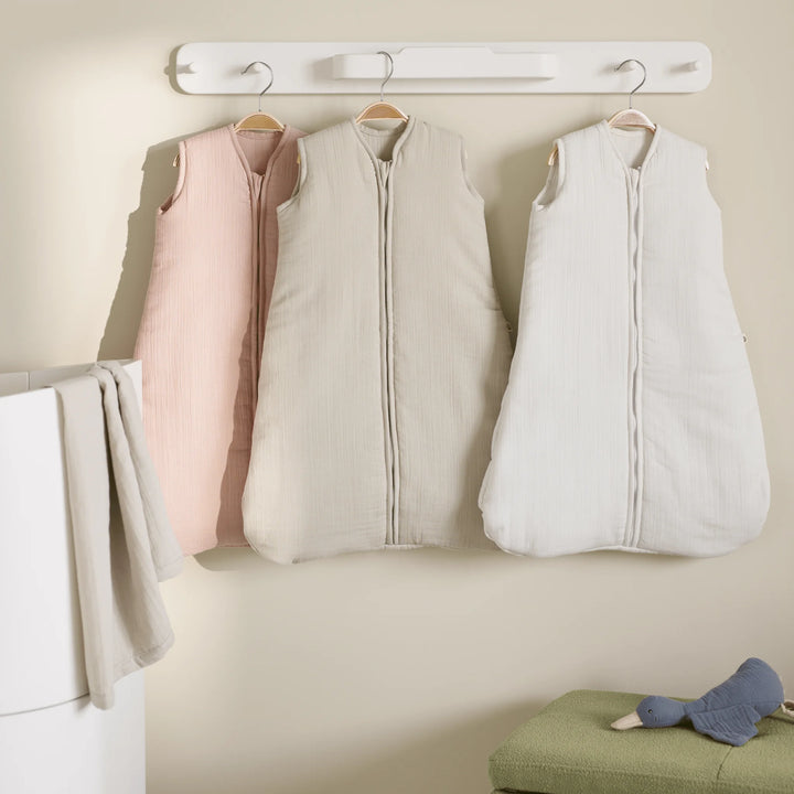 Hera white hanging rail on nursery wall next to cot with three maia muslin sleep suits hanging on the pegs.