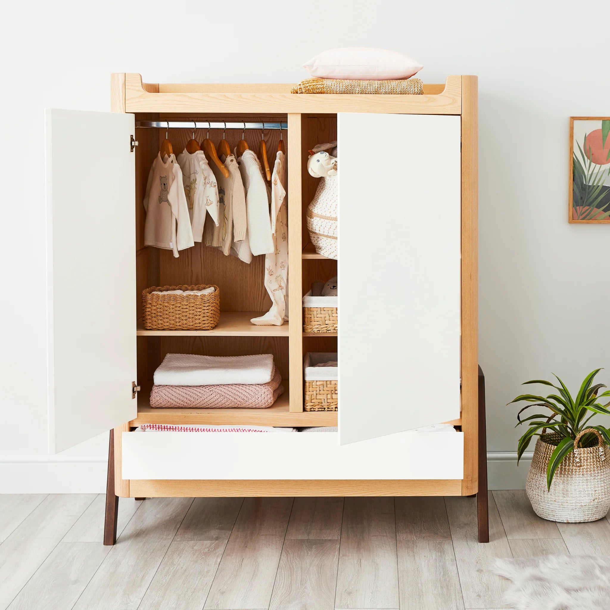 Armoire Gaia Baby Hera avec deux portes et tiroir pleine largeur ouvert rempli de vêtements de bébé suspendus, de couvertures pliées et de paniers de rangement