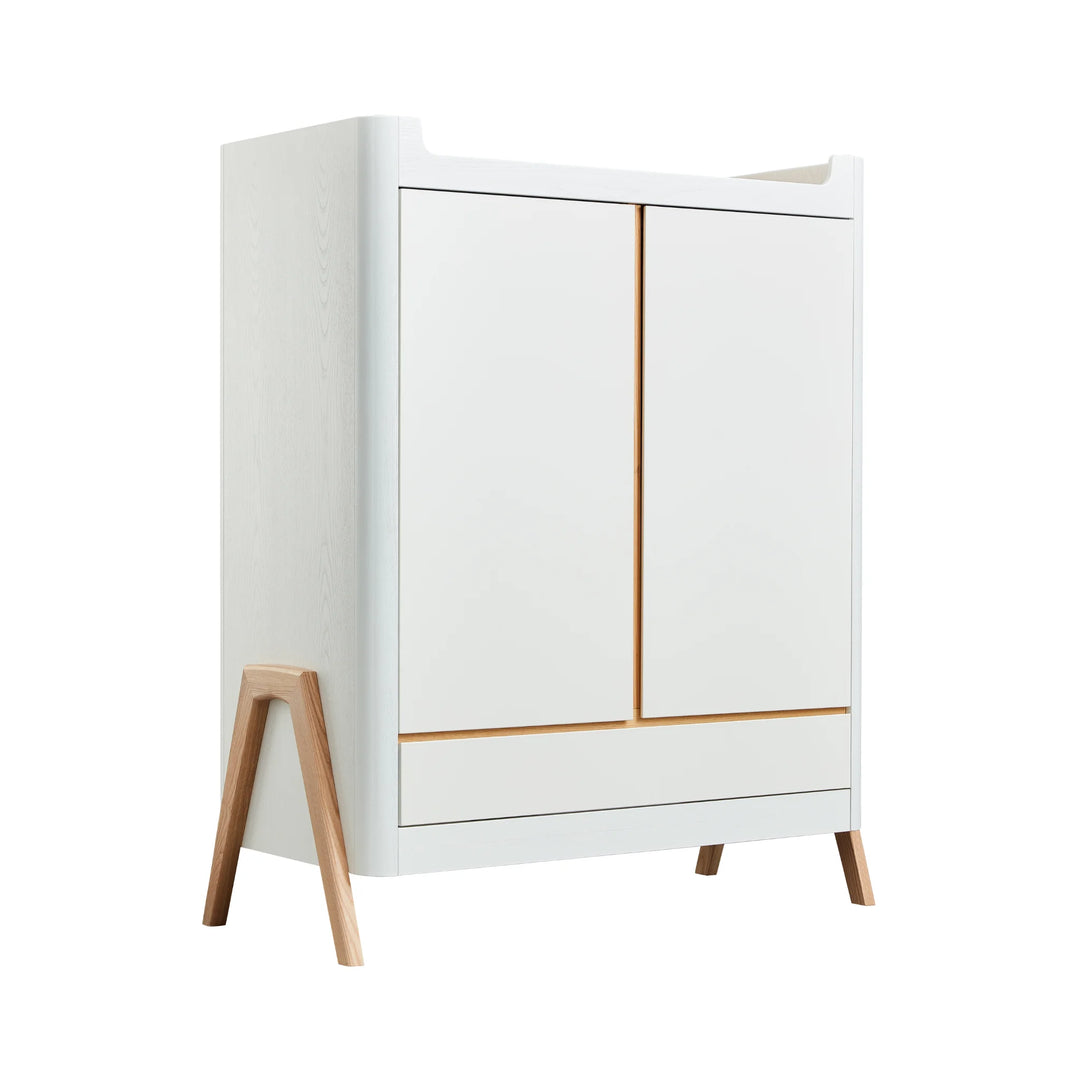 Angled view of Gaia Baby Hera nursery wardrobe in scandi white featuring 2 doors, a full width drawer and real ash wood a-frame legs.