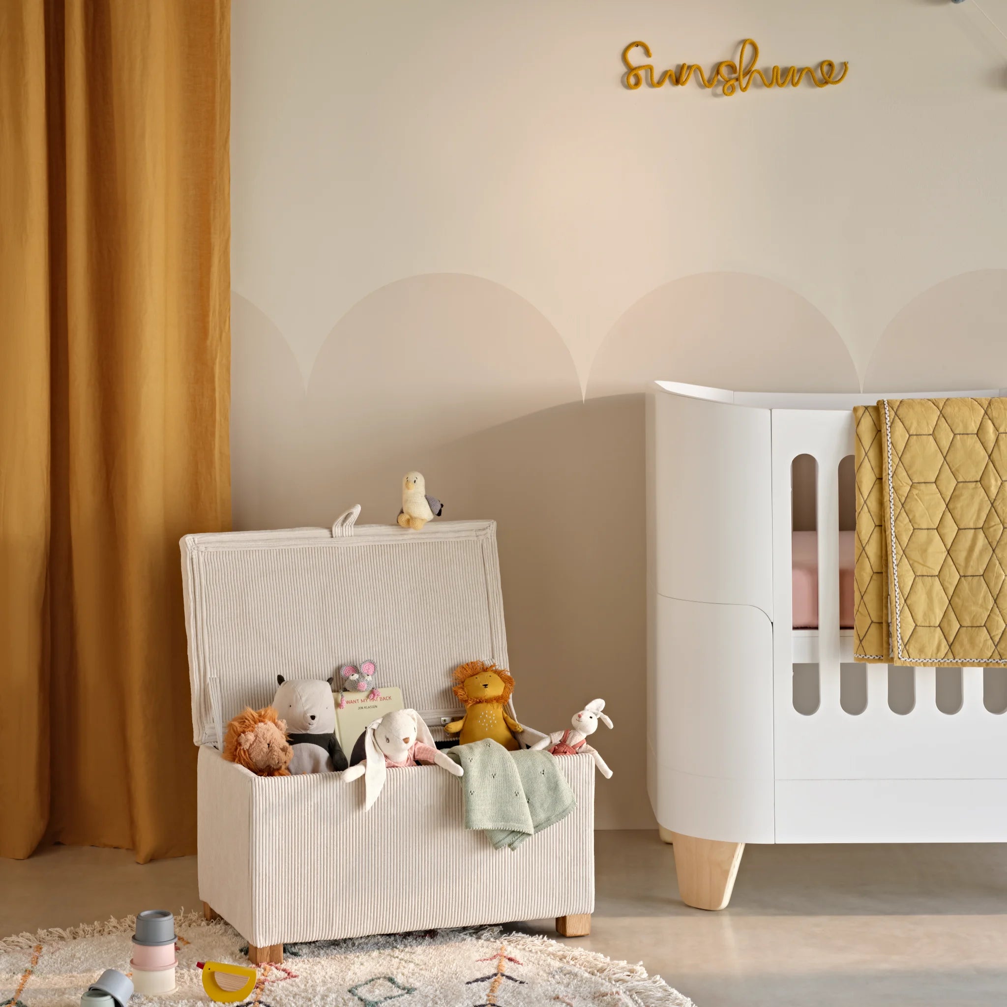 Gaia Baby Serena storage footstool in ecru corduroy used as a nursery toy box beside cot