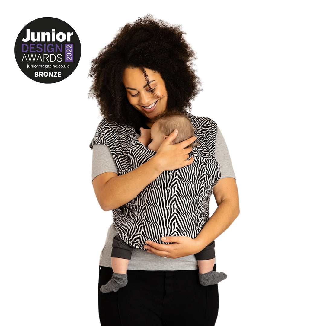Modelled image of a mother carrying her baby in Junior Design Award 2022 Bronze Winning Gaia Baby Organic Cotton Baby Wrap in okapi pattern