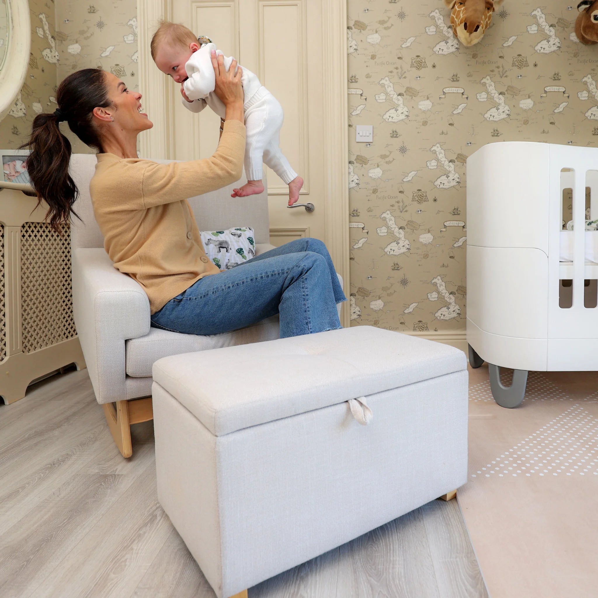 Mother holding baby in Gaia Baby Serena rocking nursing chair with matching storage footstool in nursery