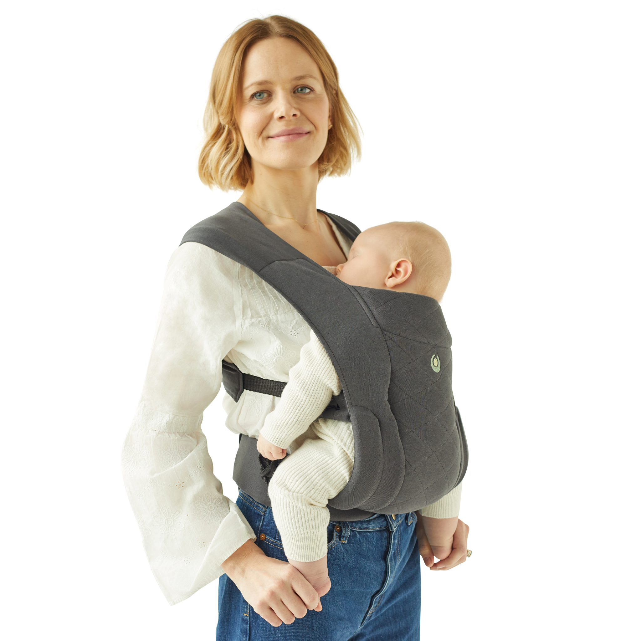 Madre rubia con la mochila portabebés Gaia Baby Newborn Plus. Su bebé duerme tranquilamente en el portabebés.