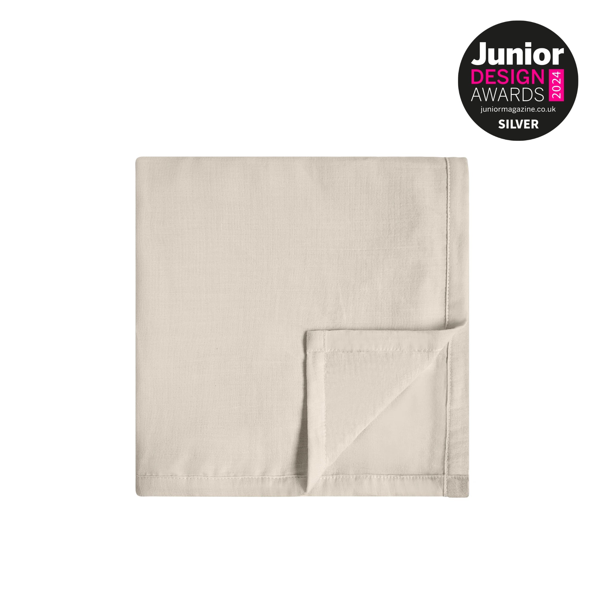 Folded sand-coloured muslin baby blanket on a clean light background with Junior Design Awards 2024 Silver badge displayed in the corner.