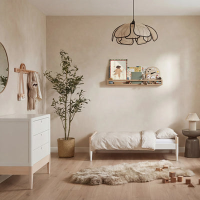 Minimalistisches Kinderzimmer mit umwandelbarem Kinderbett Gaia Baby Eos in Weiß und Naturholz, passender Kommode, neutralem Dekor und Holzboden.