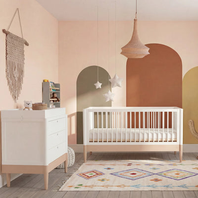 Gaia Baby EOS Cabrio-Kinderbett in Weiß mit Naturholz in einem errötenden Kinderzimmer mit gewölbtem Wanddesign, Sternenmobile und gemustertem Teppich