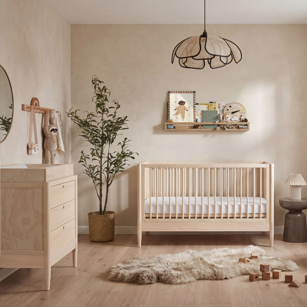 Gaia Baby Eos convertible cot and dresser set in all natural wood in a modern neutral nursery with plant, soft rug, and wooden floor