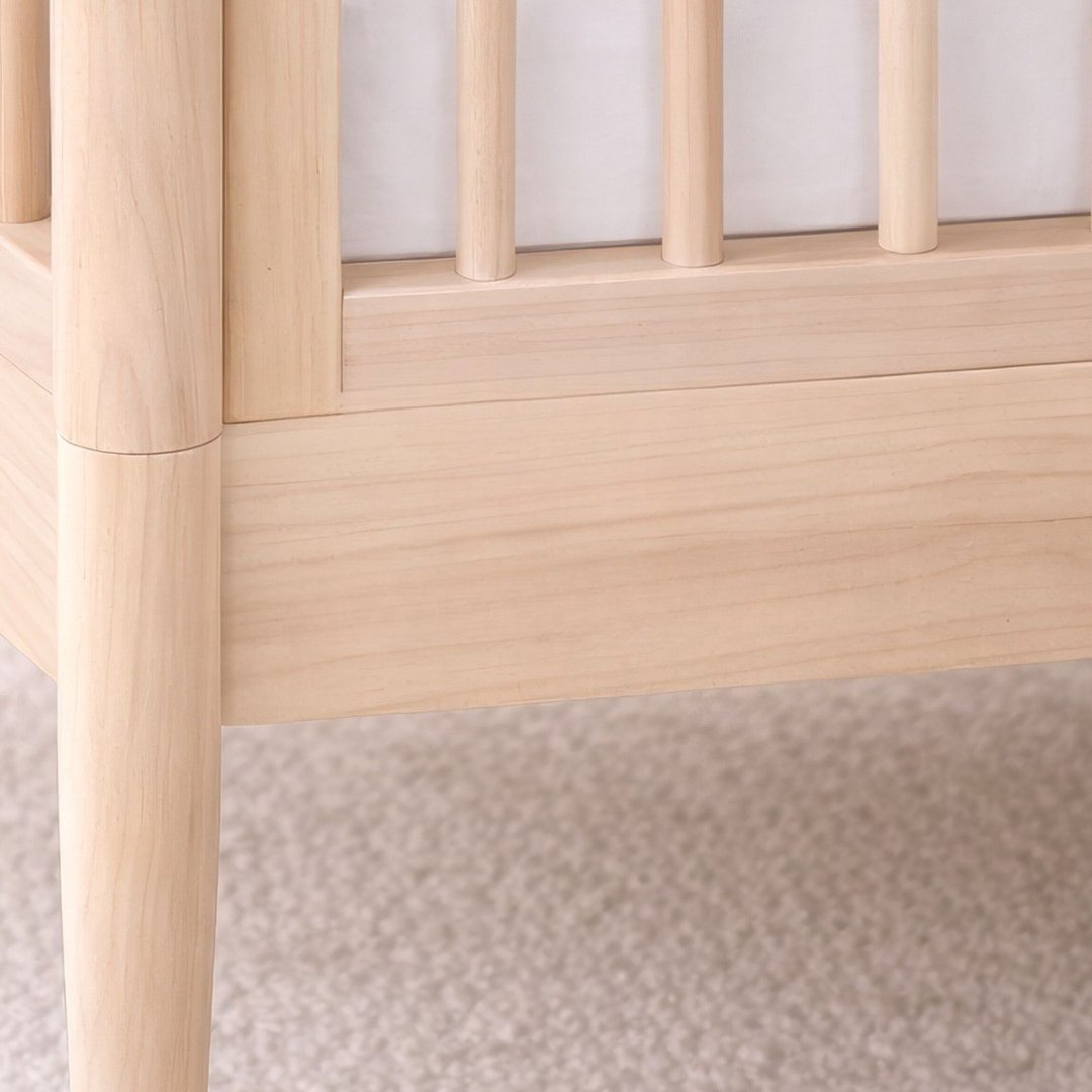 Close-up of Gaia Baby Eos cot bed in all natural wood showing rounded frame, wooden slats, and smooth finish.