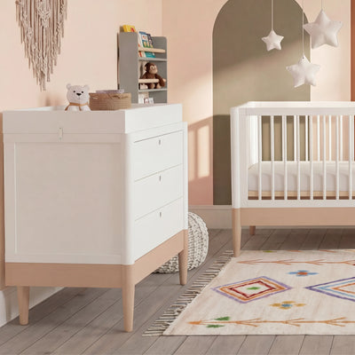 Gaia Baby EOS Kommode mit Wickelauflage in Weiß und Naturholz in einem Kinderzimmer.