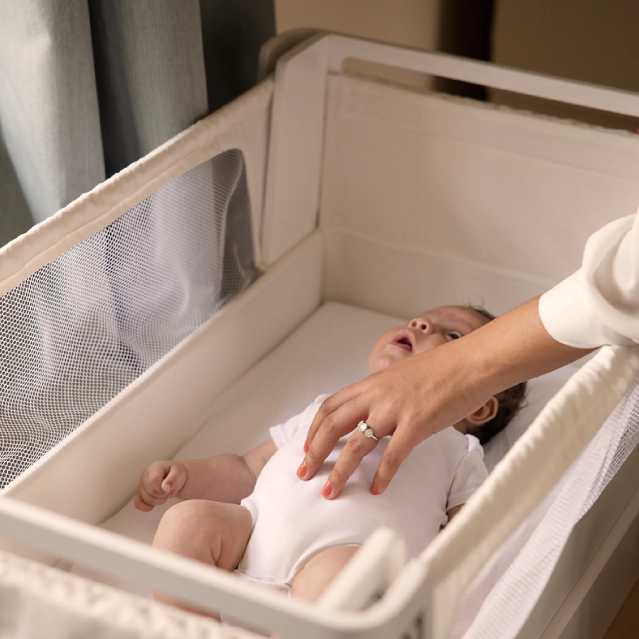 Nahaufnahme des Babys im Hera-Beistellbett in Scandi-Weiß.