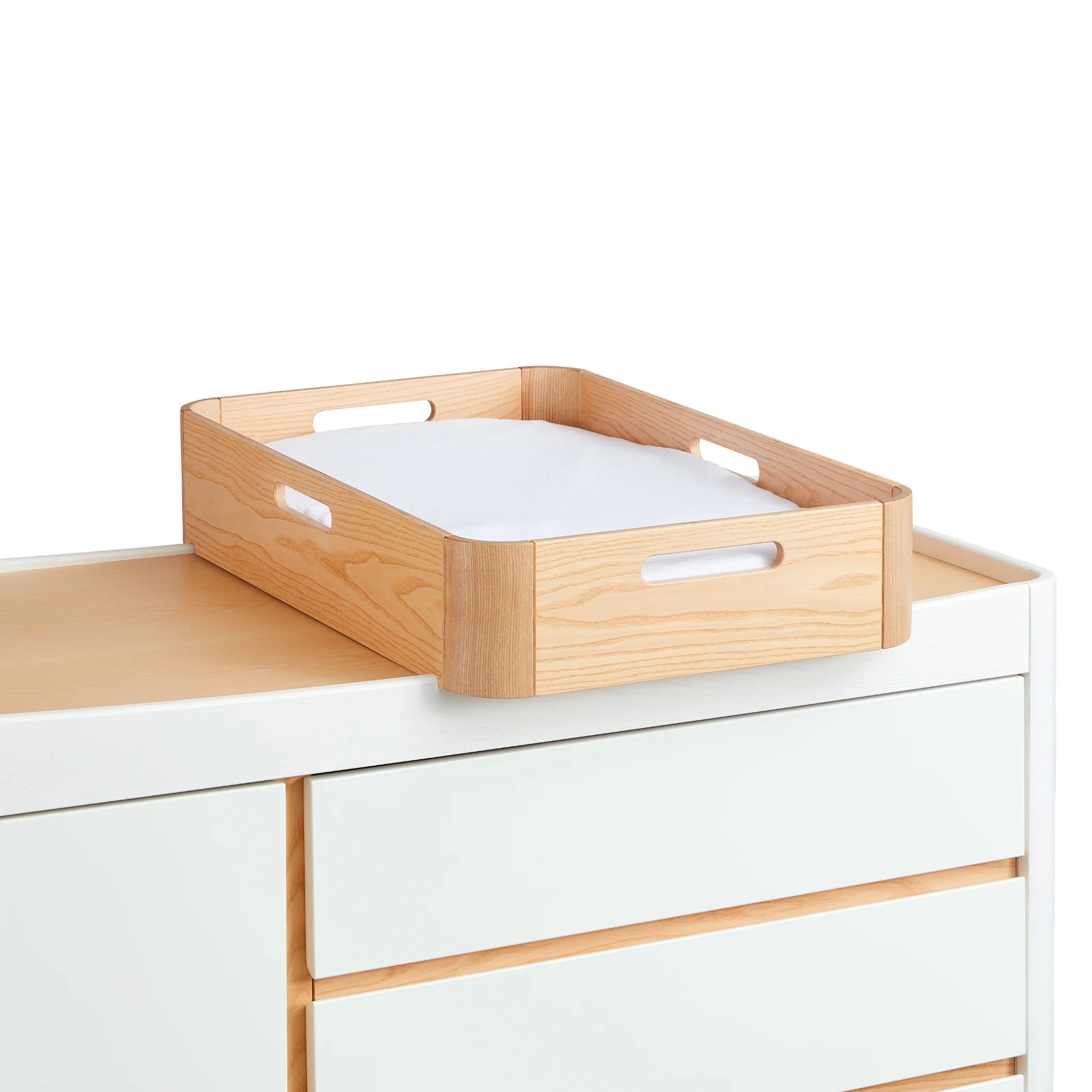Angled view of Gaia Baby Hera portable baby changing tray with soft waterproof insert sitting atop the matching Hera dresser in scandi white.
