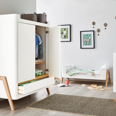 Hera-Kinderbett im First-Bed-Modus mit passendem, mit Kleidung gefülltem Kleiderschrank.