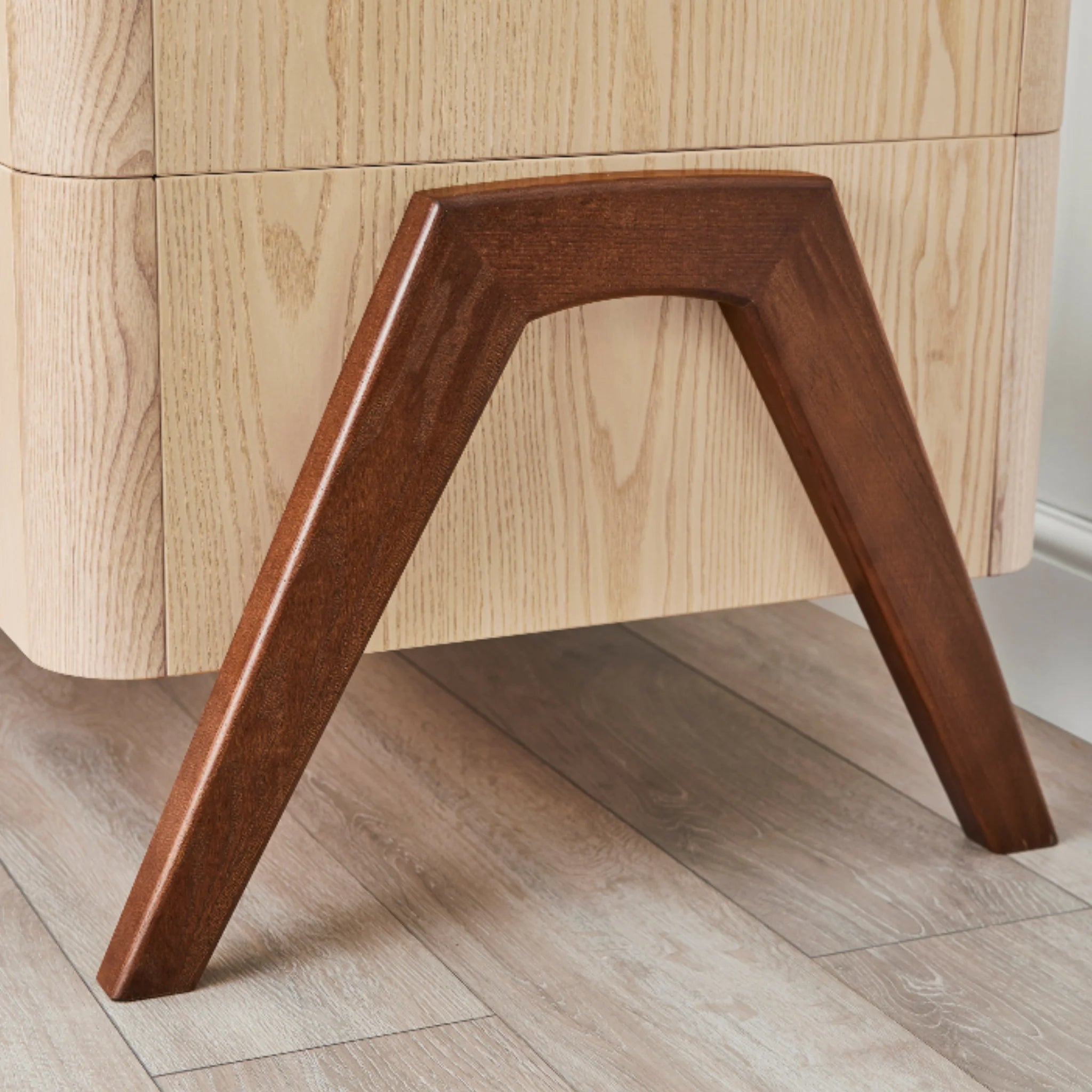 Detail of Hera cot bed by Gaia Baby showing solid walnut leg and natural ash wood frame in nursery setting.