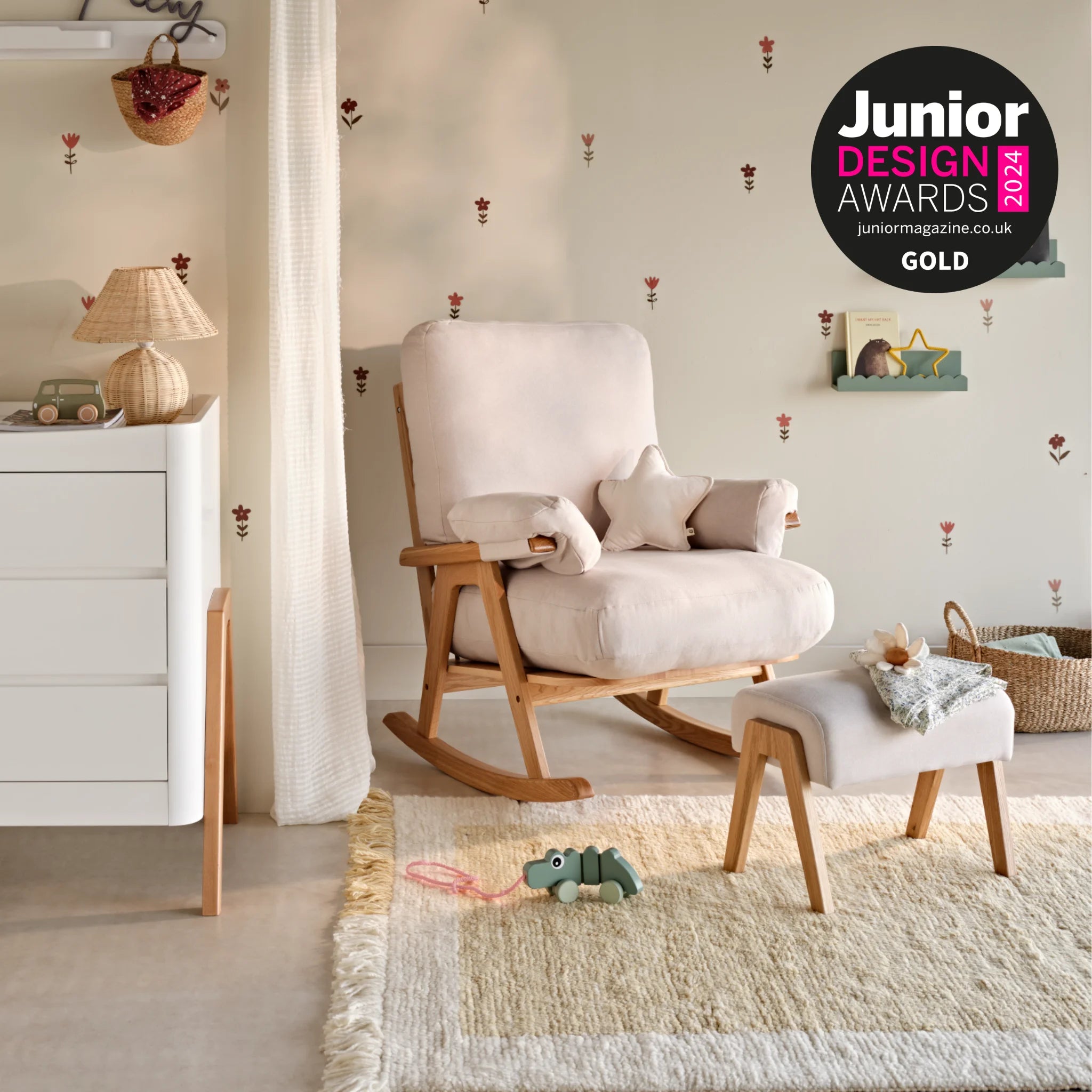 Award-winning nursery rocking chair and matching footstool with light upholstery and wooden frame, styled in a cozy nursery setting with toys, soft décor, and a Junior Design Awards 2024 Gold badge.