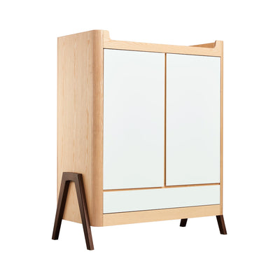Angled view of Gaia Baby Hera nursery wardrobe in white natural featuring 2 doors, a full width drawer and real walnut wood a-frame legs.