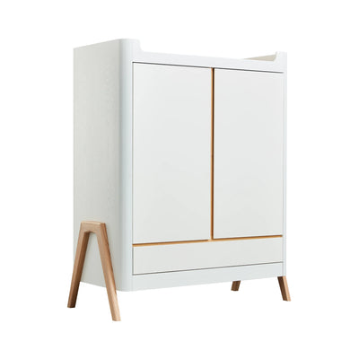 Angled view of Gaia Baby Hera nursery wardrobe in scandi white featuring 2 doors, a full width drawer and real ash wood a-frame legs.