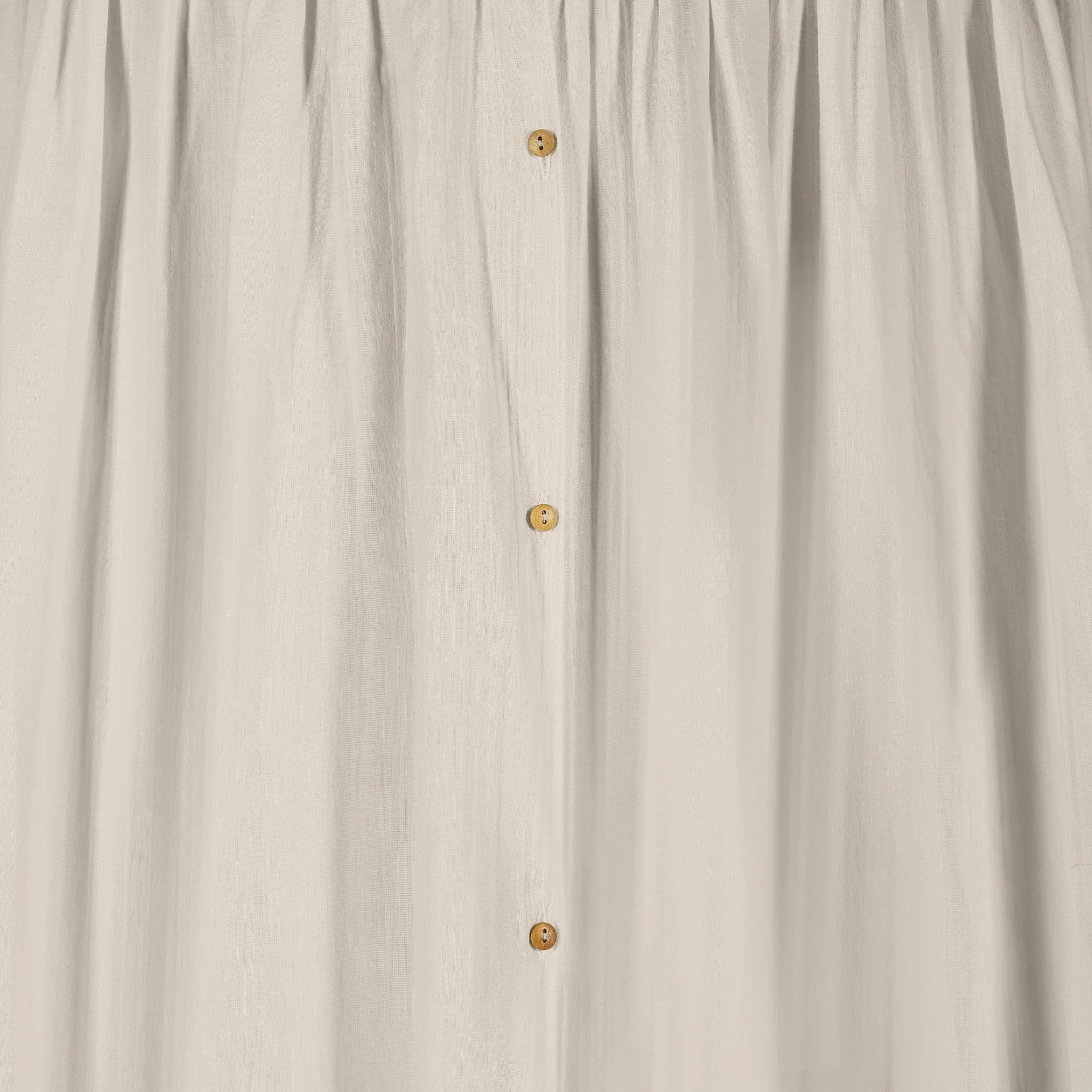 Close-up detail of the Gaia Baby Maia muslin canopy in soft sand colour, featuring lightweight textured fabric with delicate wooden button fastenings and gentle gathered draping.