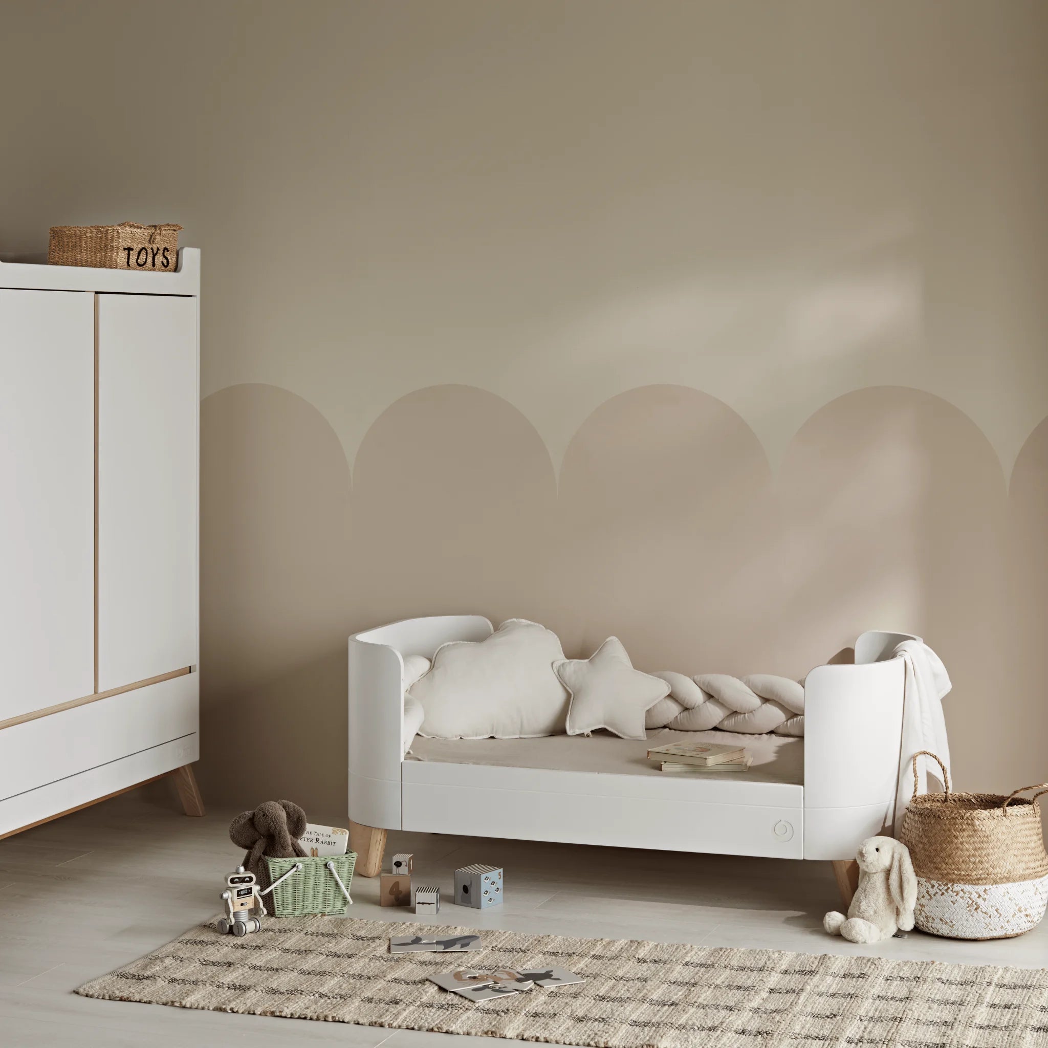 Gaia Baby Serena ledikantbed omgebouwd tot eerste bedmodus met Maia biologisch katoenen mousseline kussens en bumper. Links is de Hera kledingkast gedeeltelijk zichtbaar.