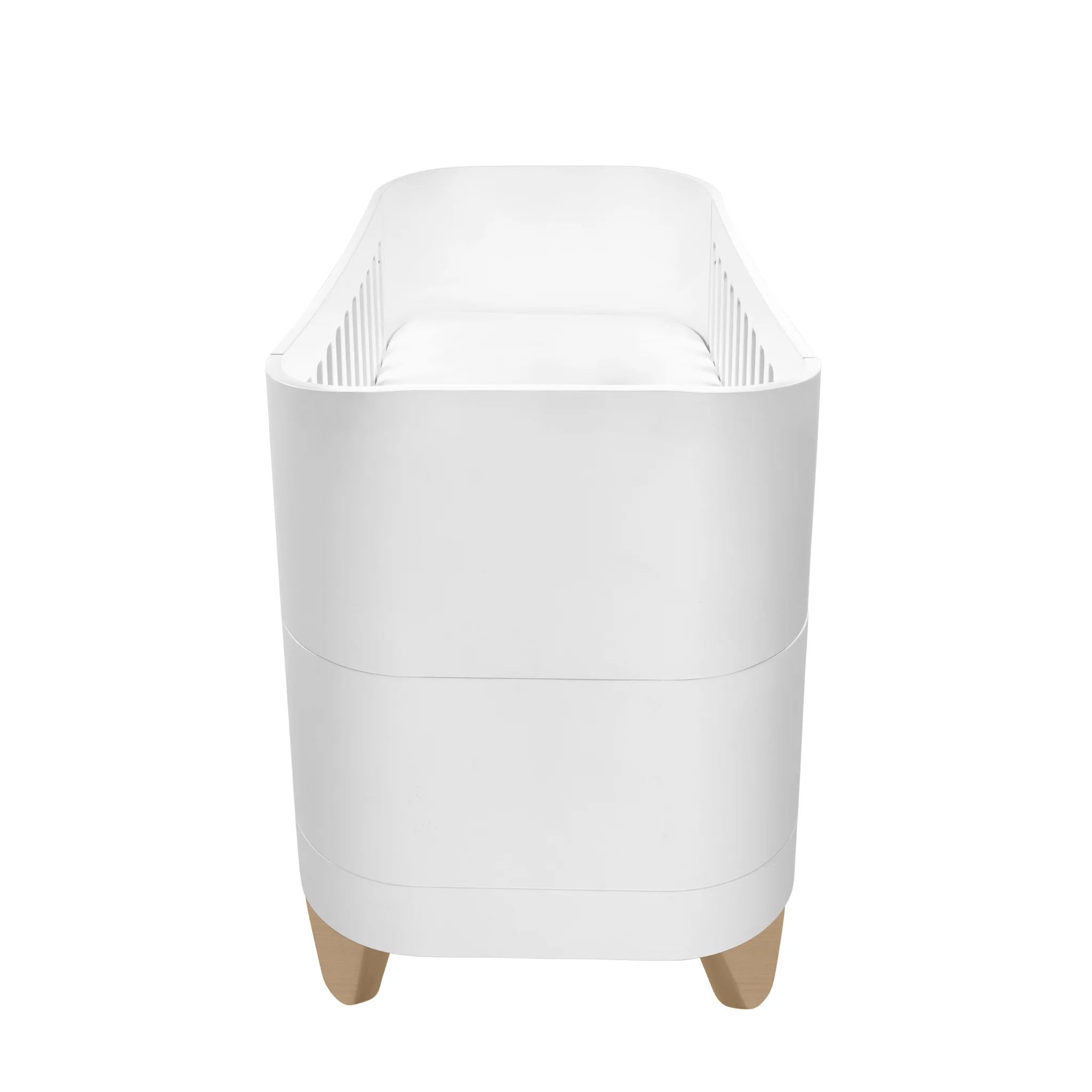 Side profile view of the white Serena cot bed with smooth curved edges, slatted interior sides, and natural wood legs on a clean white background.
