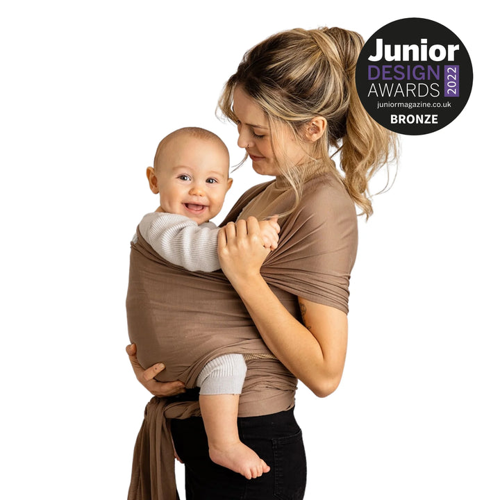 Modelled image of a mother carrying her baby in Junior Design Award 2022 Bronze Winning Gaia Baby Organic Cotton Baby Wrap in nutmeg colour
