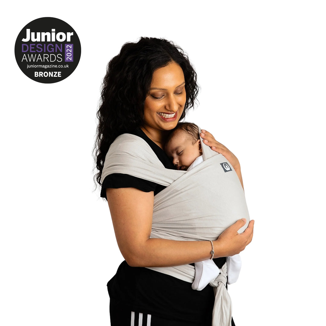 Modelled image of a mother carrying her baby in Junior Design Award 2022 Bronze Winning Gaia Baby Organic Cotton Baby Wrap in silver grey colour