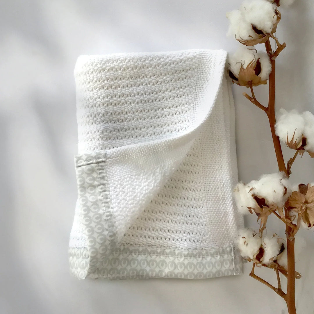 Lifestyle Image of Gaia Baby Newborn Blanket in white. folded blanket