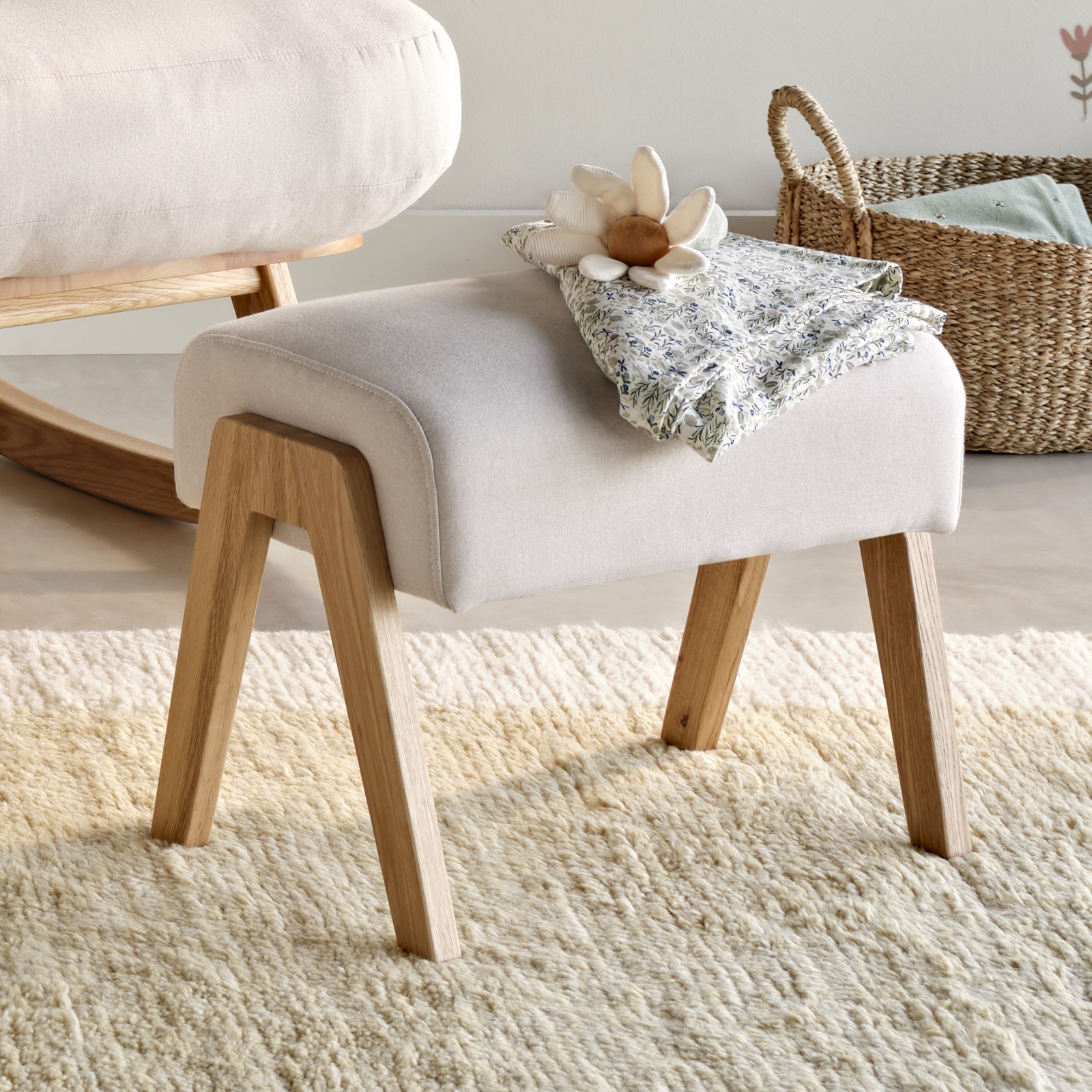 Hera footstool in barley lifestyle image with woven basket in the background and cream carpet.