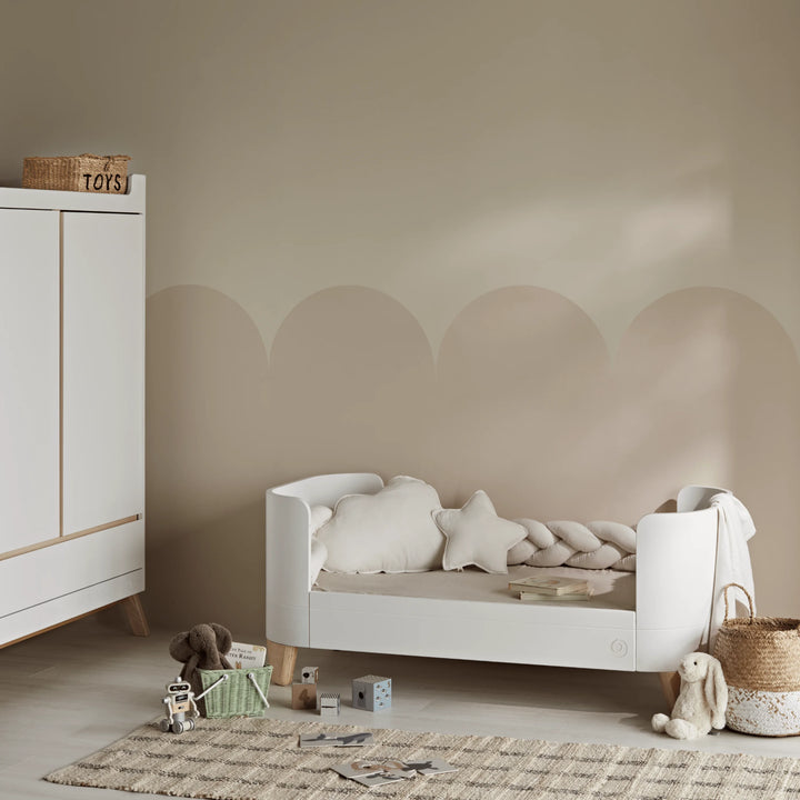 Gaia Baby Serena Cot Bed converted to toddler bed, white kids bed with soft furnishings in modern neutral nursery interior.
