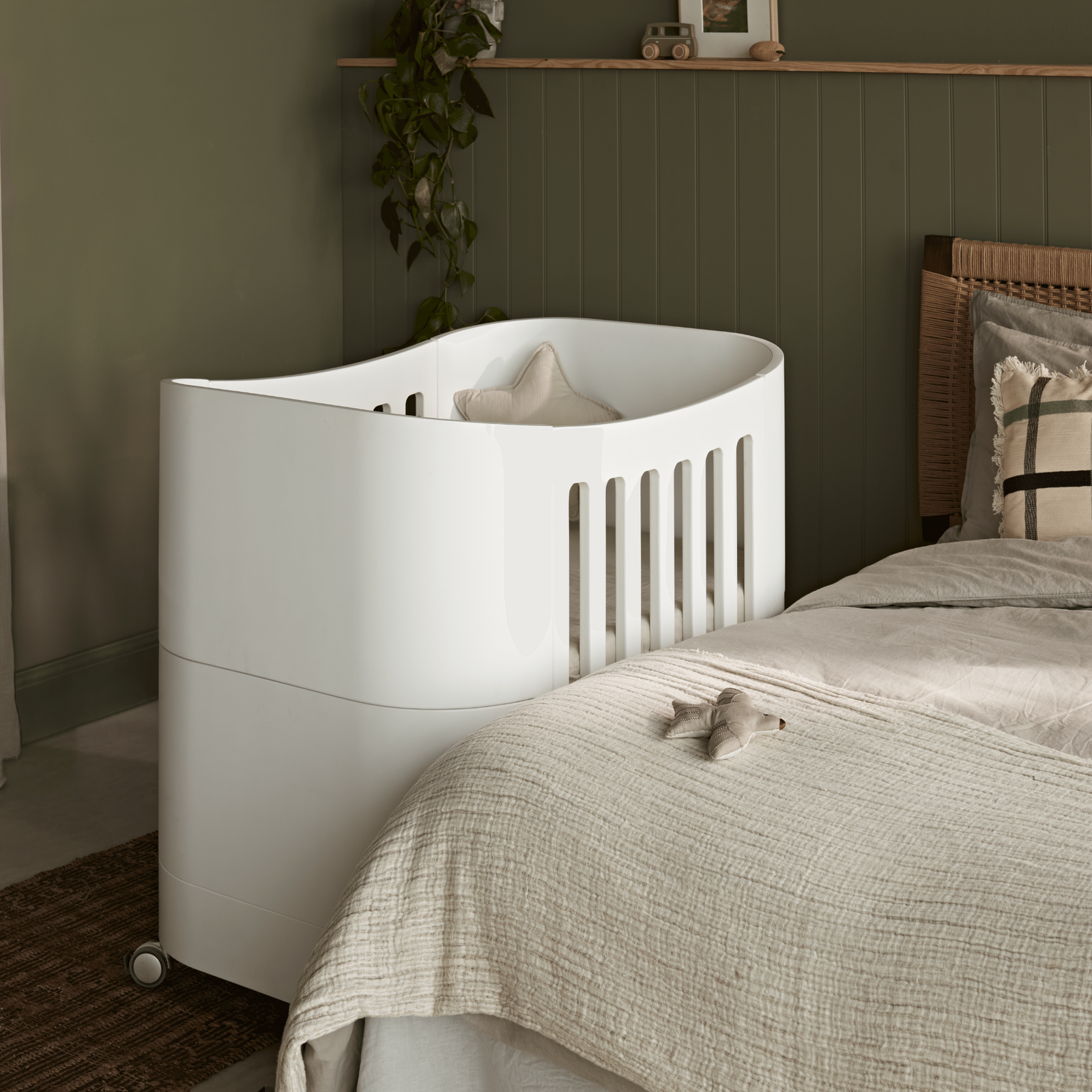 product image of Gaia baby Serena mini Cot with wheels next to the parent's bed