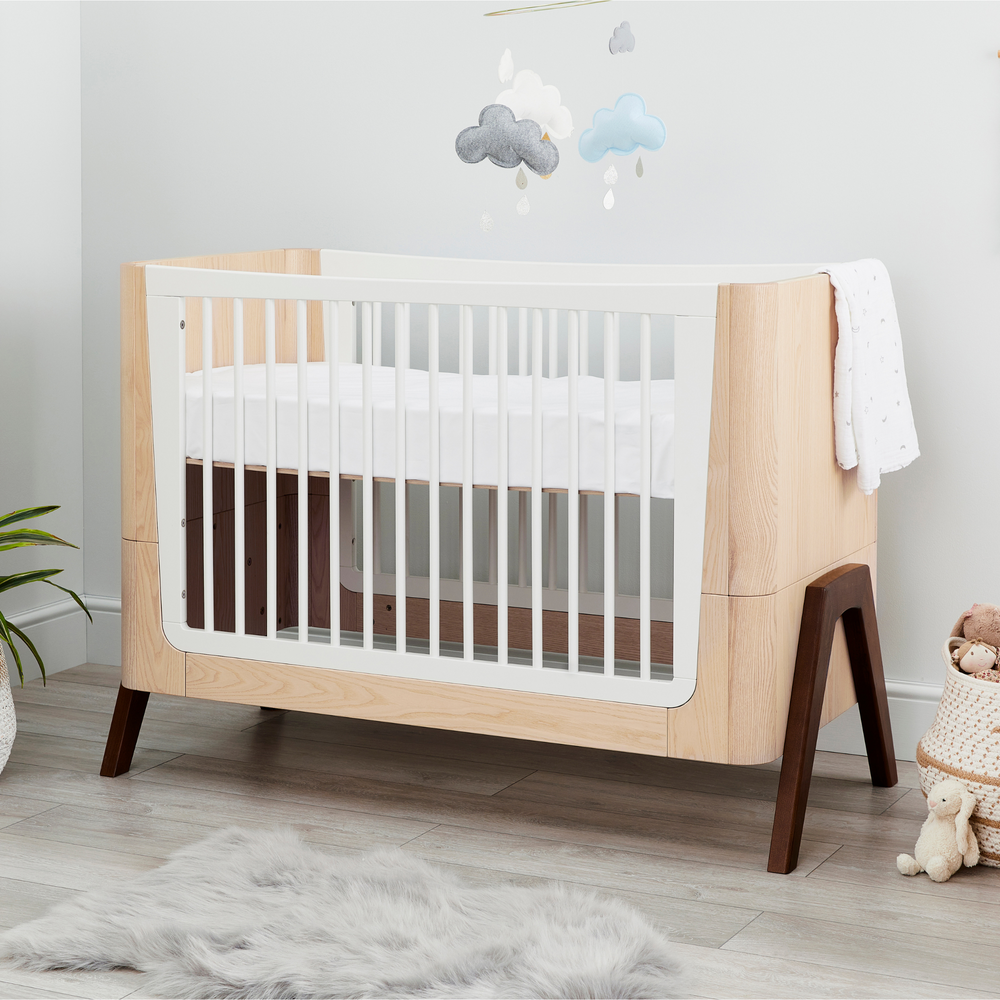 This is a lifestyle image of the Hera Cot Bed in a nursery with a felt mobile above the cot