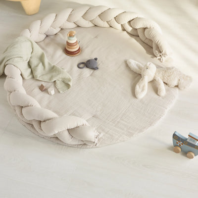 Ein Lifestyle-Bild einer Baby-Spielecke mit dem Gaia-Baby, dem geflochtenen Maia-Musselin-Kissen und der Maia-Spielmatte